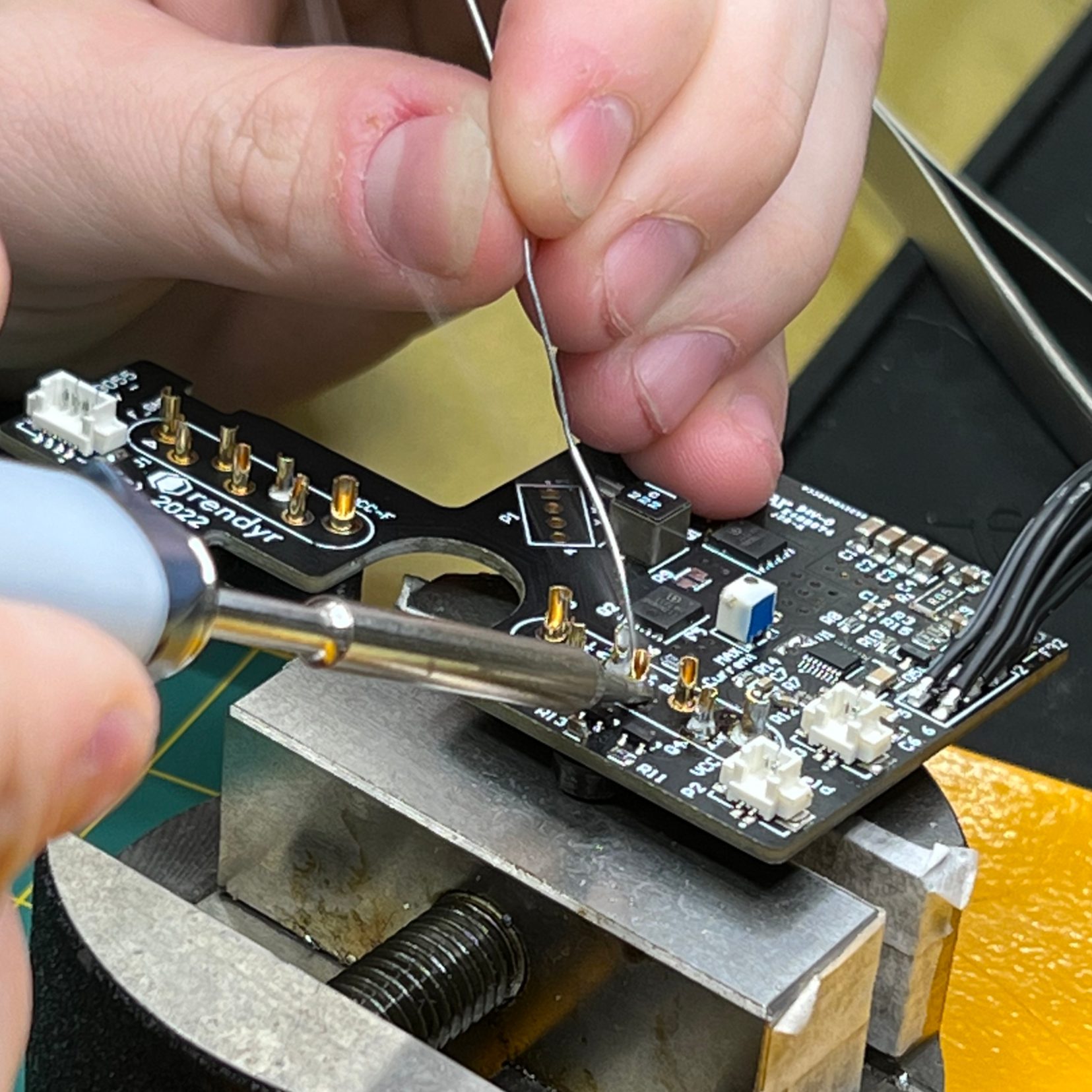 Soldering a PCB at the bench vise.